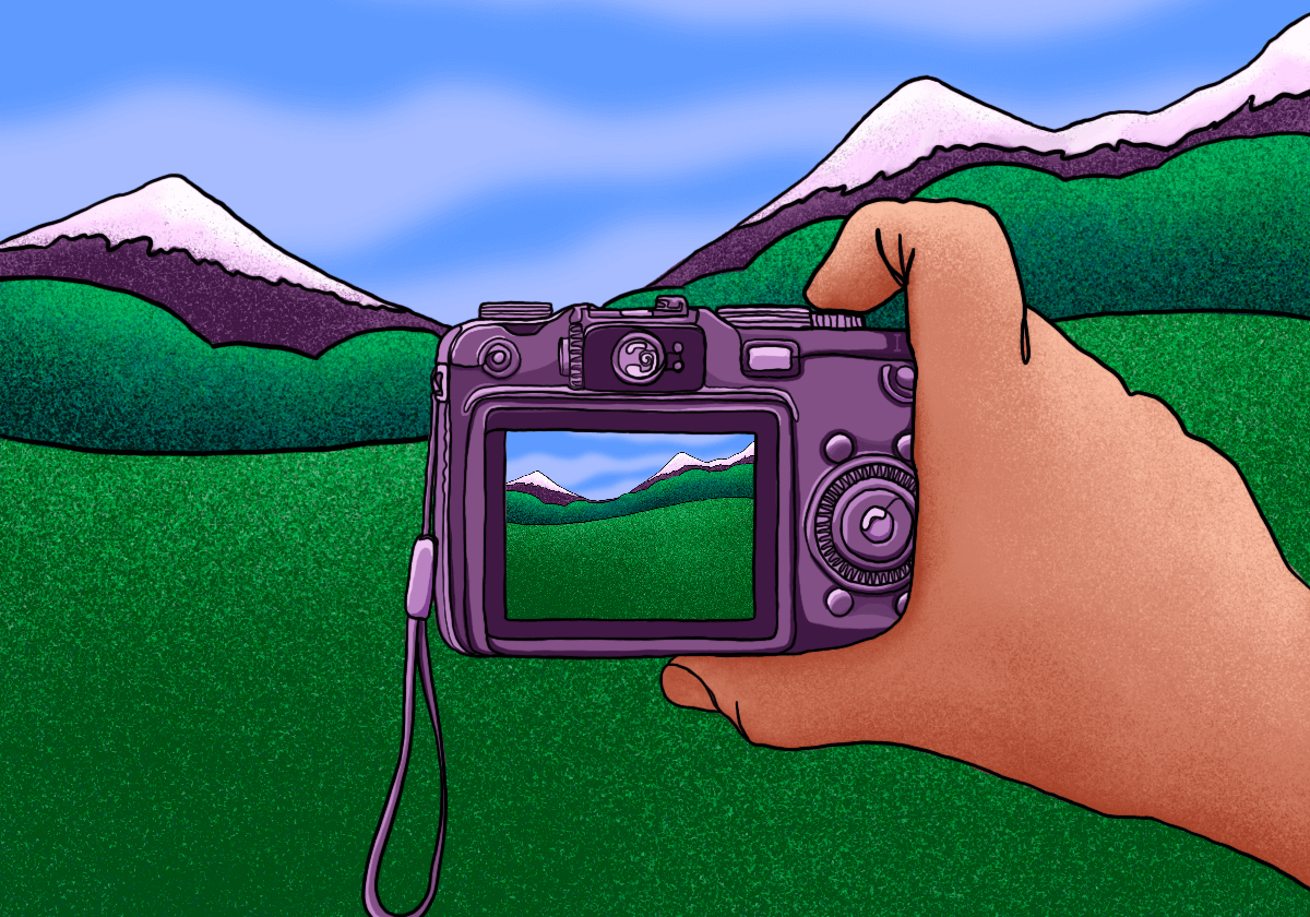 Hand holding camera capturing snowy mountains.